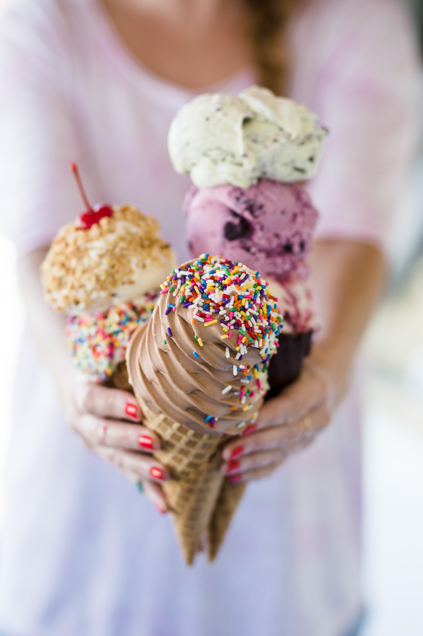 A handful of ice cream and frozen yogurt cones with colorful sprinkles